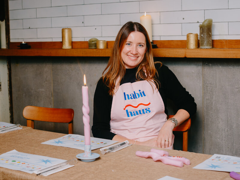 Harri Price of Habit Haus, sits at a table with bendy candles in front of her